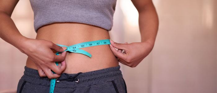 a girl measuring her waist 